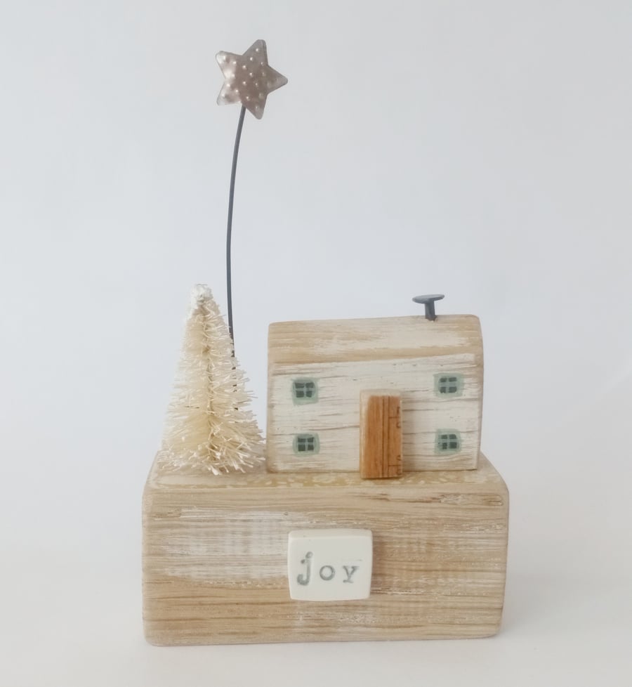 Wooden house with Christmas tree and star 'joy'