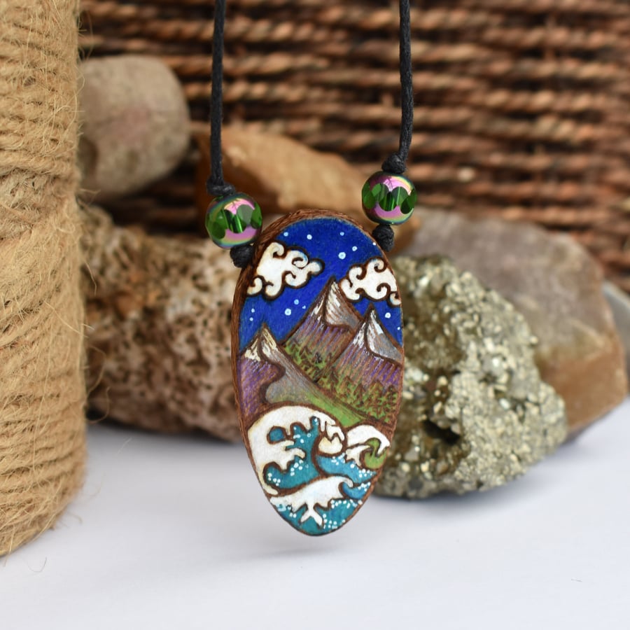 Mountains and waves under a twilight sky. Wooden oval pendant.