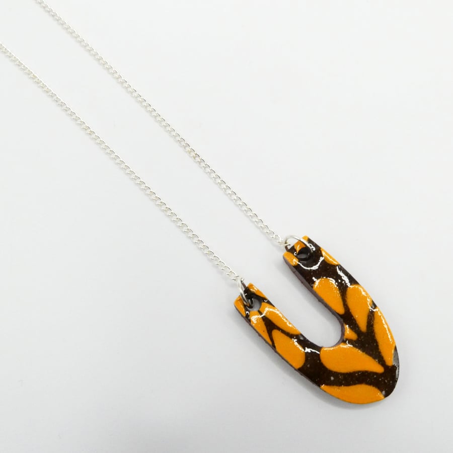 Ceramic U pendant in orange and brown on a curb chain necklace