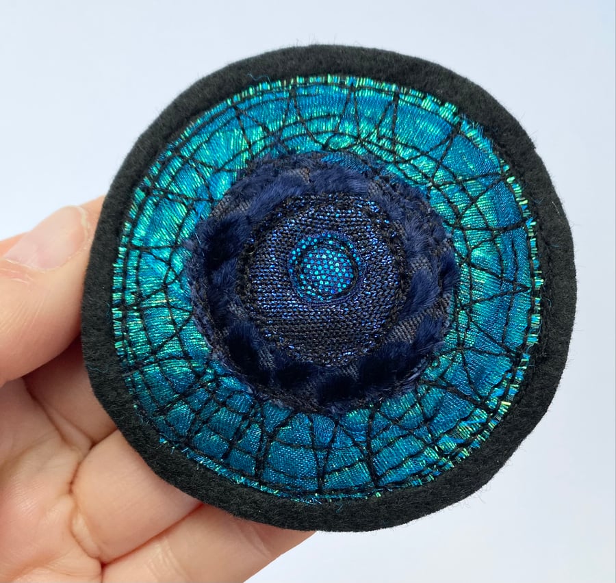 Embroidered circular sun brooch pin of badge. 