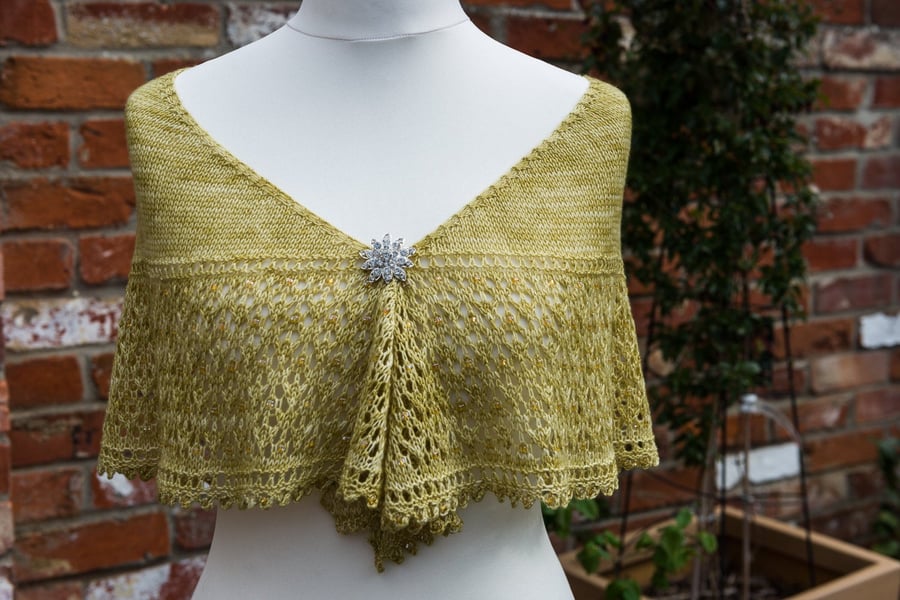 Shawl hand knit in a crescent shape using a green yellow coloured soft yarn