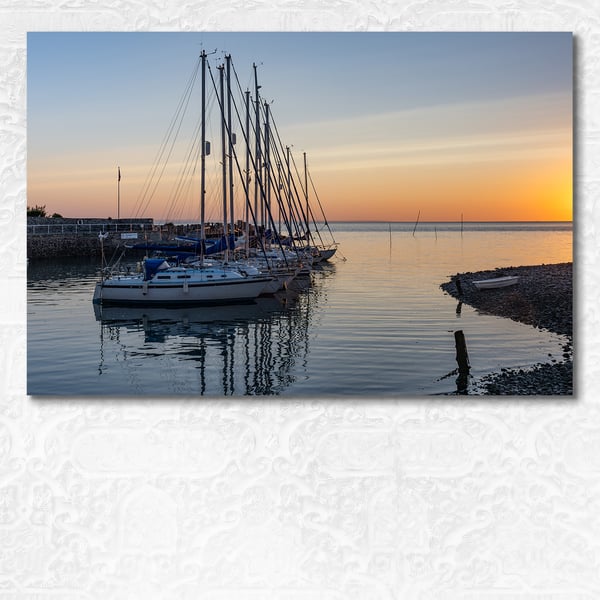 Yachts at anchor on calm water in Porlock Weir, Devon at sunrise 