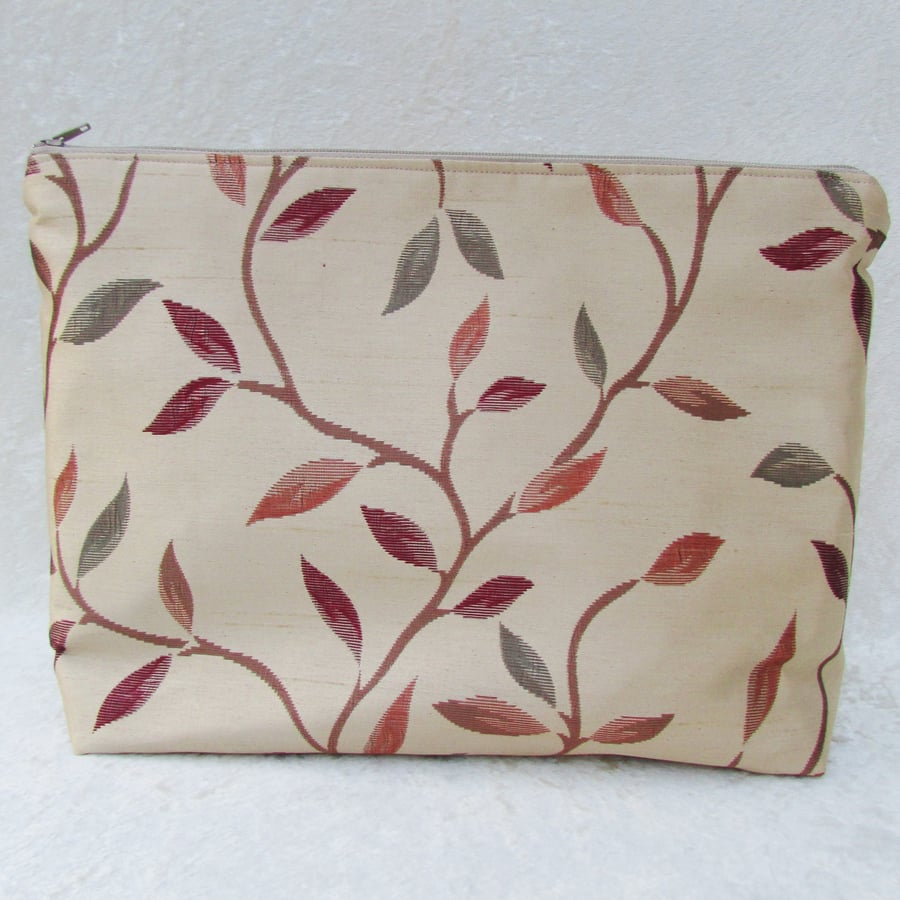 Gold fabric toiletry bag with dark red and terracotta leaf pattern