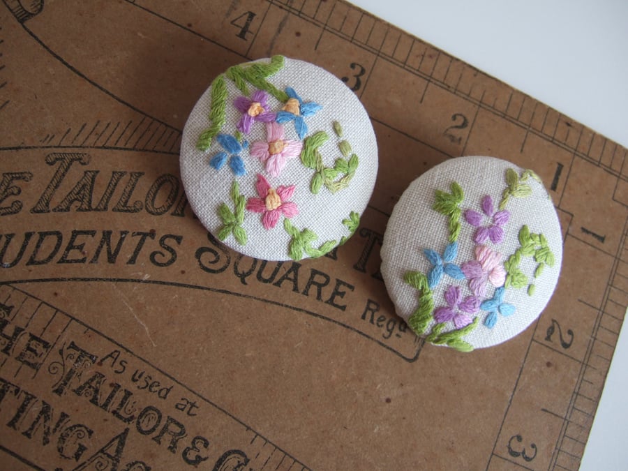A pair of extra-large buttons covered in vintage floral hand embroidery