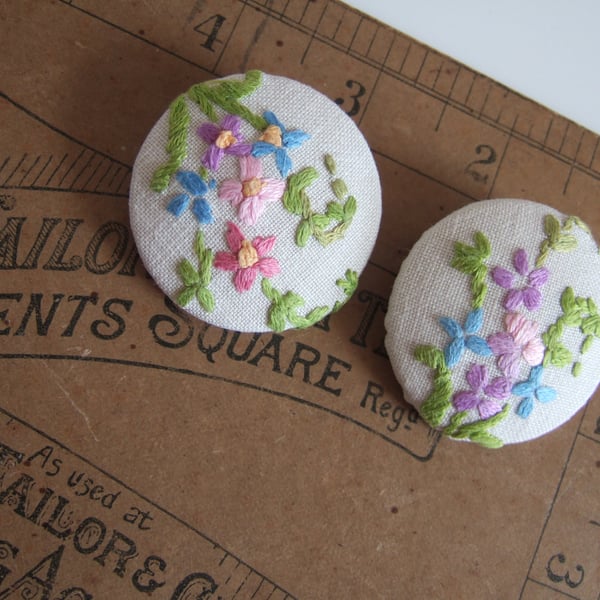 A pair of extra-large buttons covered in vintage floral hand embroidery