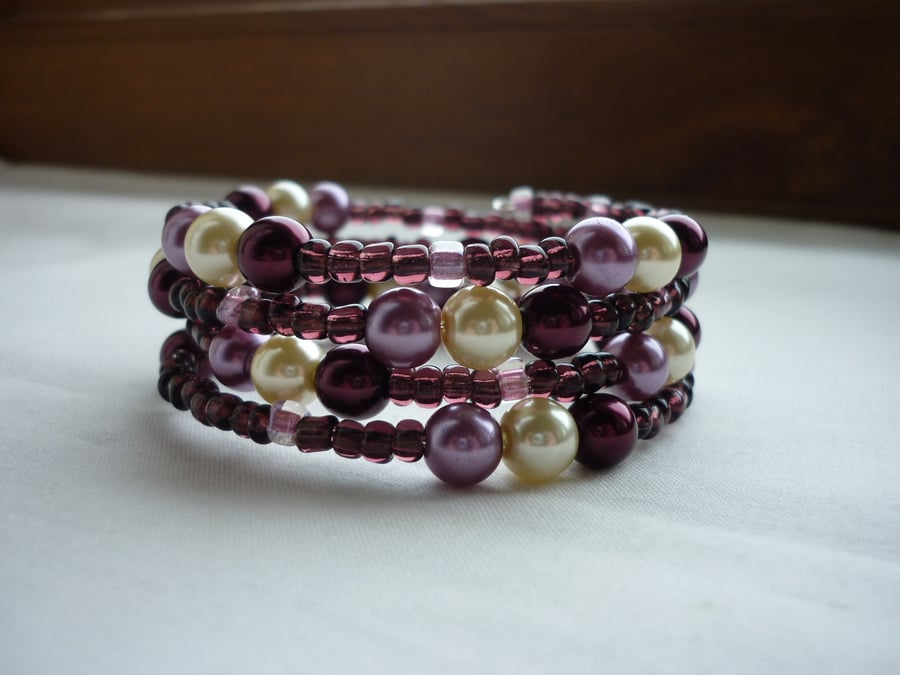 BURGUNDY, OFF WHITE AND LILAC FROST MEMORY WIRE BRACELET.  416