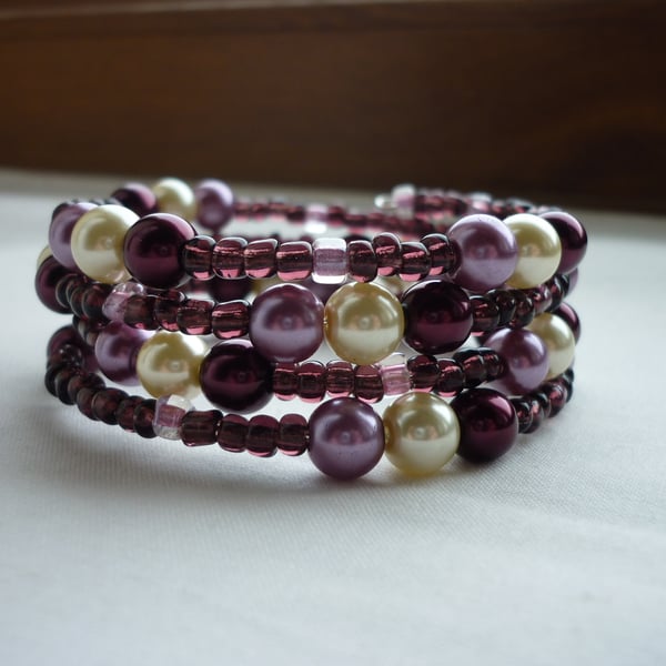 BURGUNDY, OFF WHITE AND LILAC FROST MEMORY WIRE BRACELET.  416