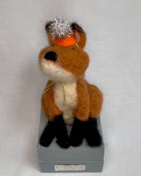 Handcrafted needle felted fox with removable party hat on a wooden box