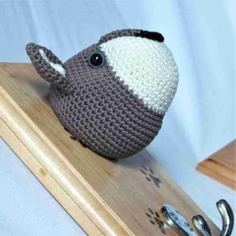 Crocheted wolf-type dog head on wooden board with hooks