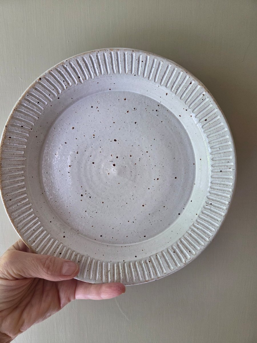White speckled deep pottery plate with incised decorative edging 