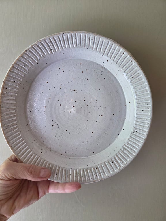 White speckled deep pottery plate with incised decorative edging 