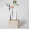 Clay flowers and heart on a wood block 'love' 