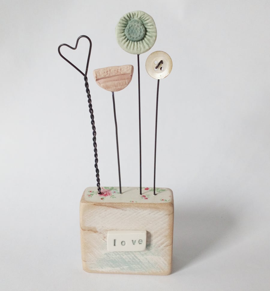 Clay flowers and heart on a wood block 'love' 