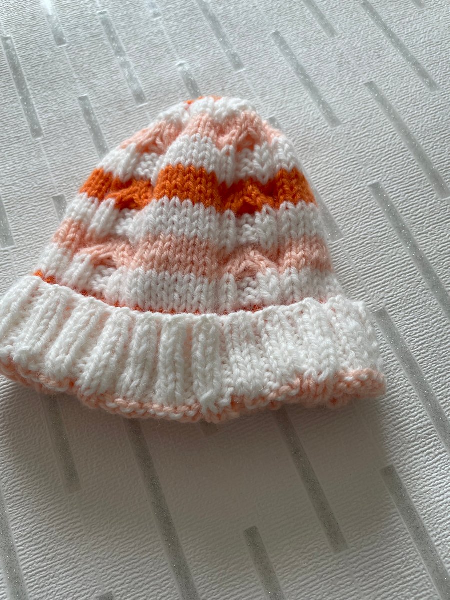 Hand knitted striped baby hat with cable pattern 