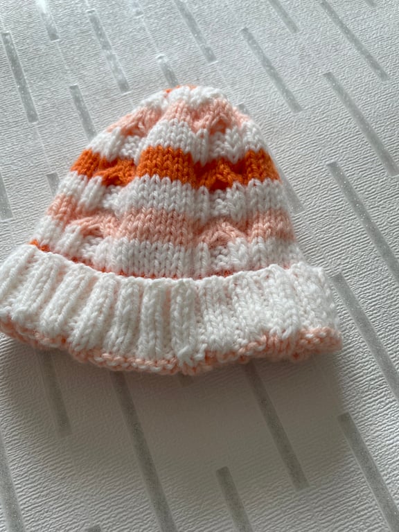 Hand knitted striped baby hat with cable pattern 