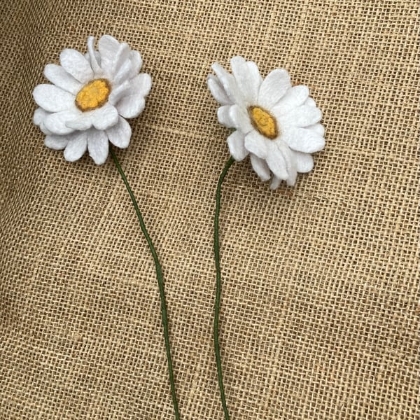 Two white needle felted daisy stems.