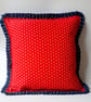 Red polkadot cushion cover with a navy polkadot pleated edge.  