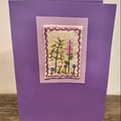 Hand embroidered purple card depicting a range of wild flowers