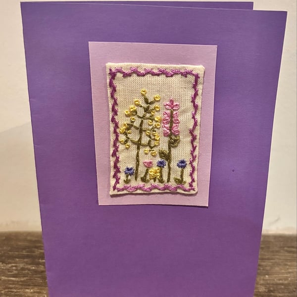 Hand embroidered purple card depicting a range of wild flowers