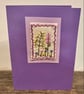 Hand embroidered purple card depicting a range of wild flowers