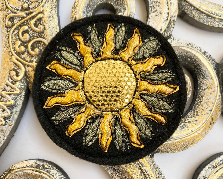 Embroidered gold circular sun brooch pin of badge. 