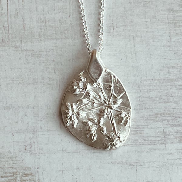 Botanical silver pendant with dill seed head design.