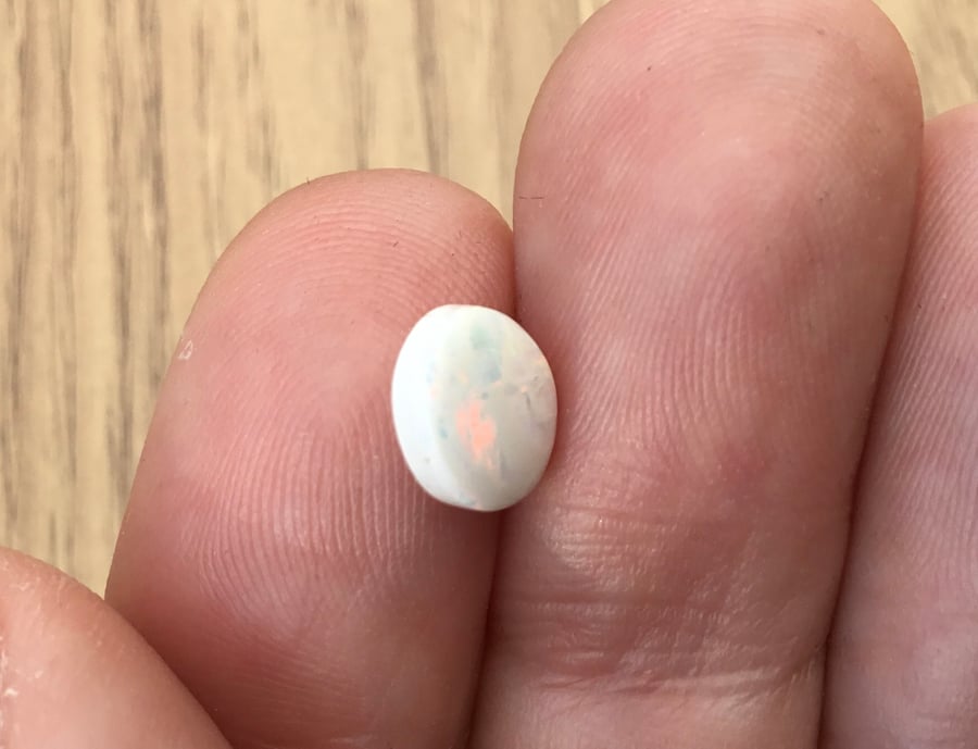 A Delicate White Lightning Ridge Opal Cabochon with Peach, Green and Blue Fire.