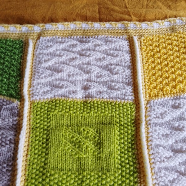 Baby or toddler handmade knitted blanket in a yellow and green theme.