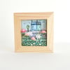 Fabric picture of houses and flowers, in a small wooden frame