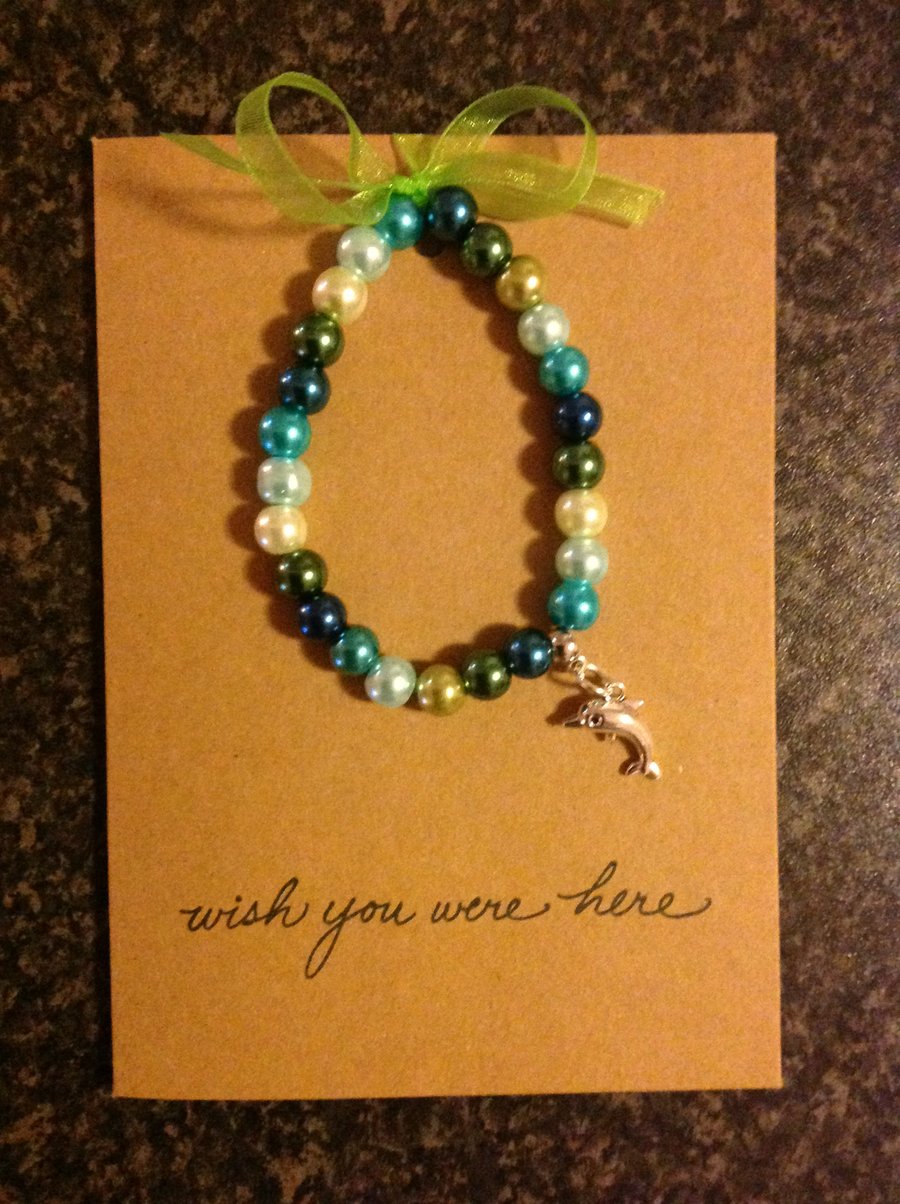 Stretch bracelet, hand strung, with charm attached, on an A6 card.