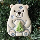 Ceramic polar bear carrying a Christmas tree decoration