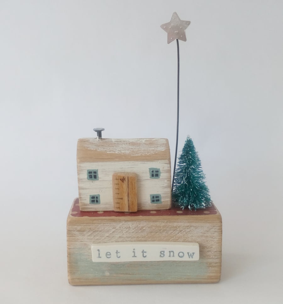 Little wooden house with Christmas tree and star 'let it snow'