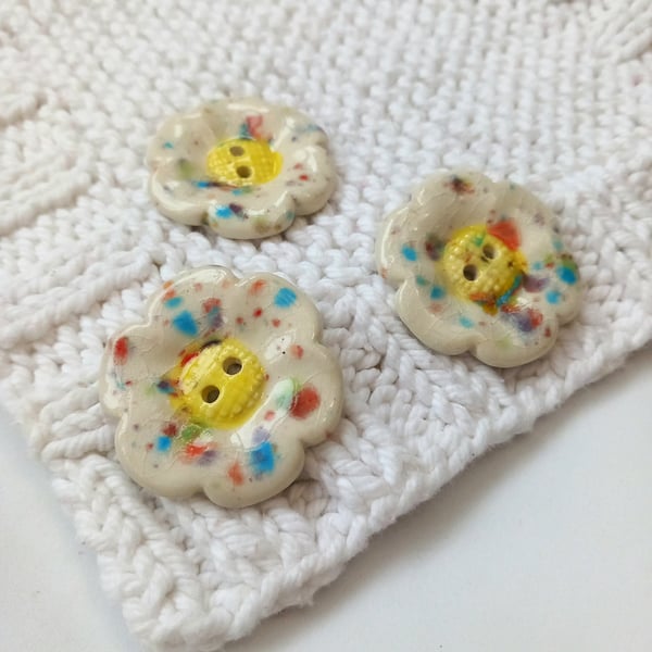 Large flower shaped cute buttons in multicolour and yellow on white. 3.5cm