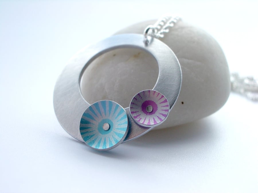 Silver coloured aluminium circle pendant with pink and blue discs