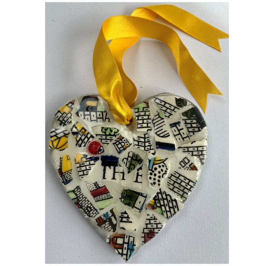 A heart shaped mosaic pendant with stylistic walls and the letters T, H and E.