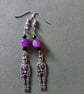 Silver skeleton dangle earrings with purple and black beads