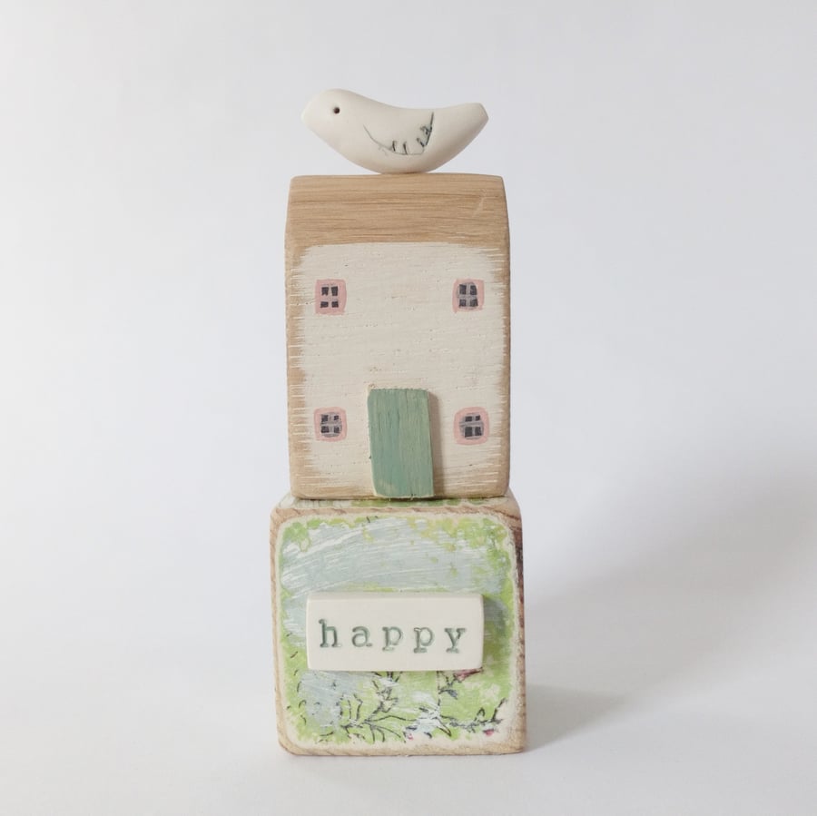 Little wooden house with clay bird on a vintage toy block
