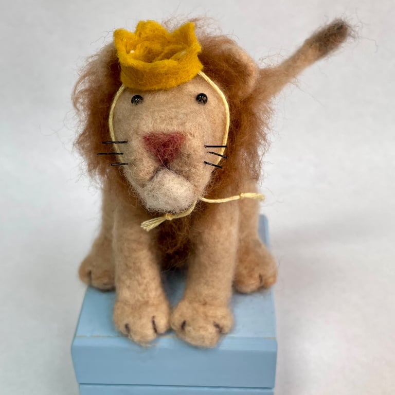 Handcrafted needle felted lion with removable party hat on a wooden box