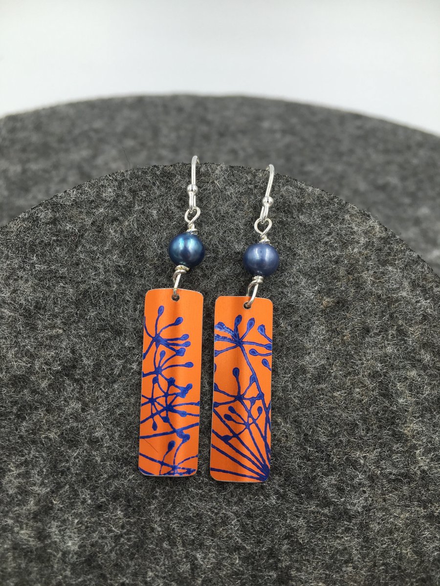 Orange anodised aluminium dangly cow parsley earrings with pearl.