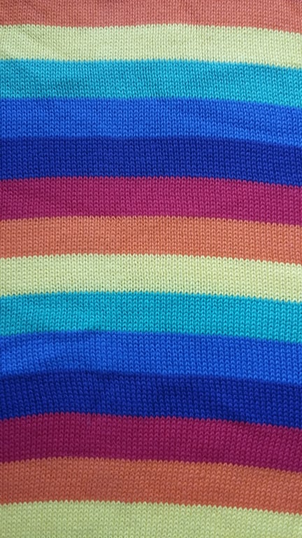 Baby blanket in rainbow striped cotton. Plain back, reversible.