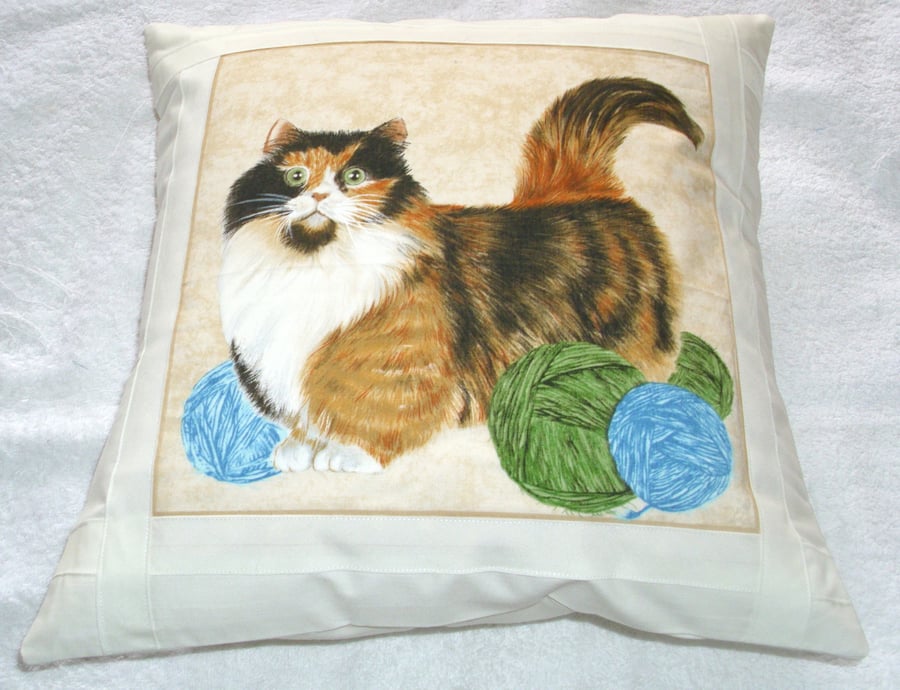 Pretty Tortoiseshell and white cat with balls of wool cushion