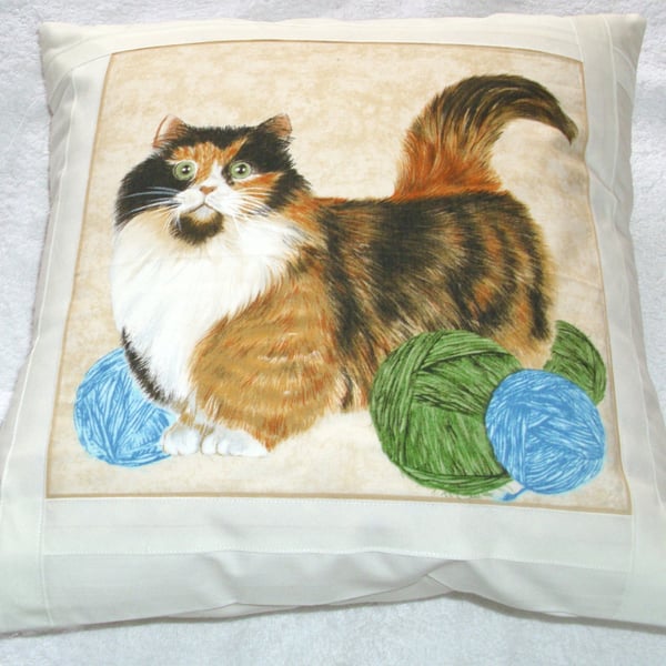 Pretty Tortoiseshell and white cat with balls of wool cushion