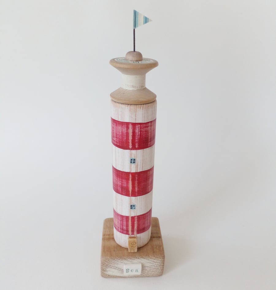 Wooden lighthouse with vintage bobbin 40 and flag 'Sea'