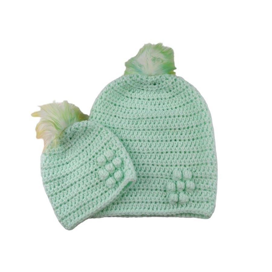 Matching ladies and baby green crocheted hats with detachable faux fur pompoms