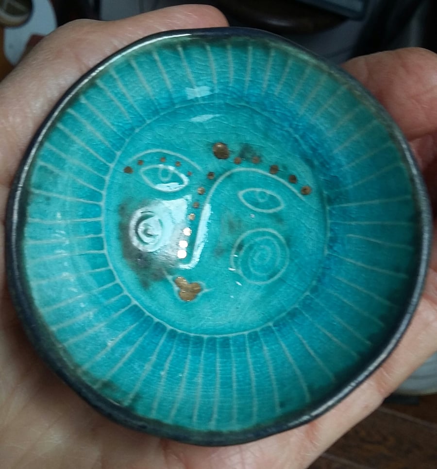 Small bowl with raised sun face motif. 