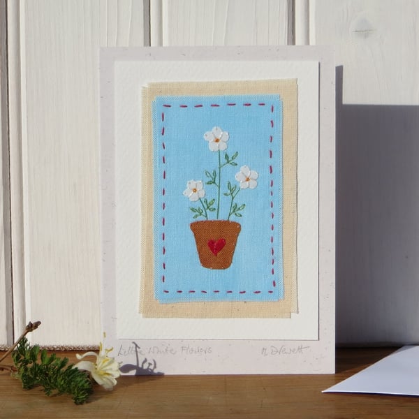 Hand-stitched little white  flowers in a pot with embroidered leaves 