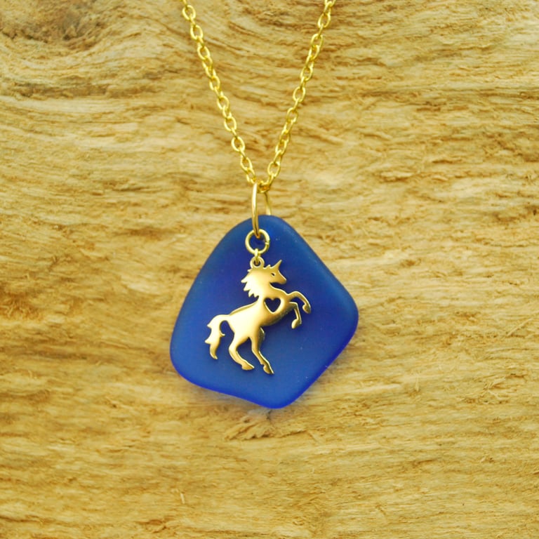 Gold horse charm on beach glass