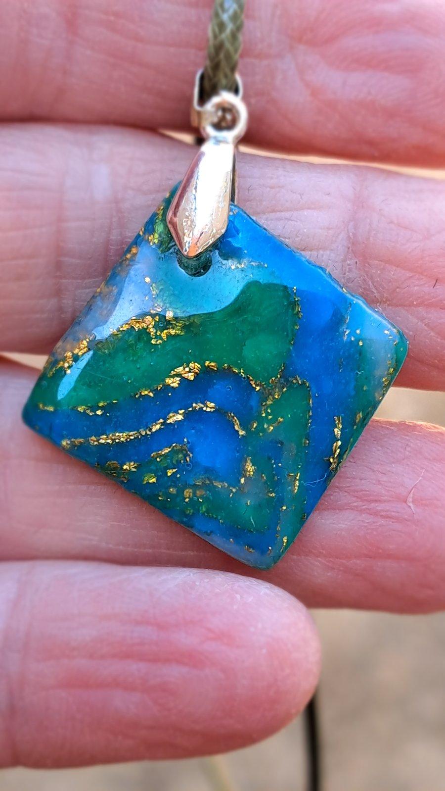 Dark green, blue, white and gold flecked square pendant on a rope necklace