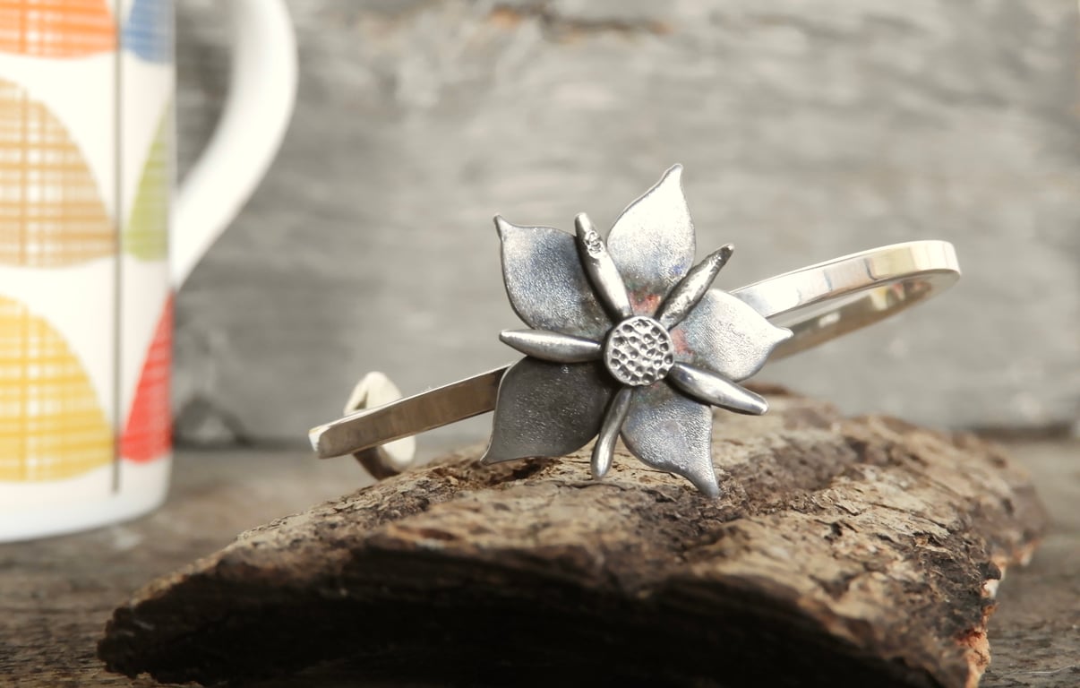 Small sterling silver open ended bangle with a silver periwinkle flower