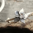 Small sterling silver open ended bangle with a silver periwinkle flower